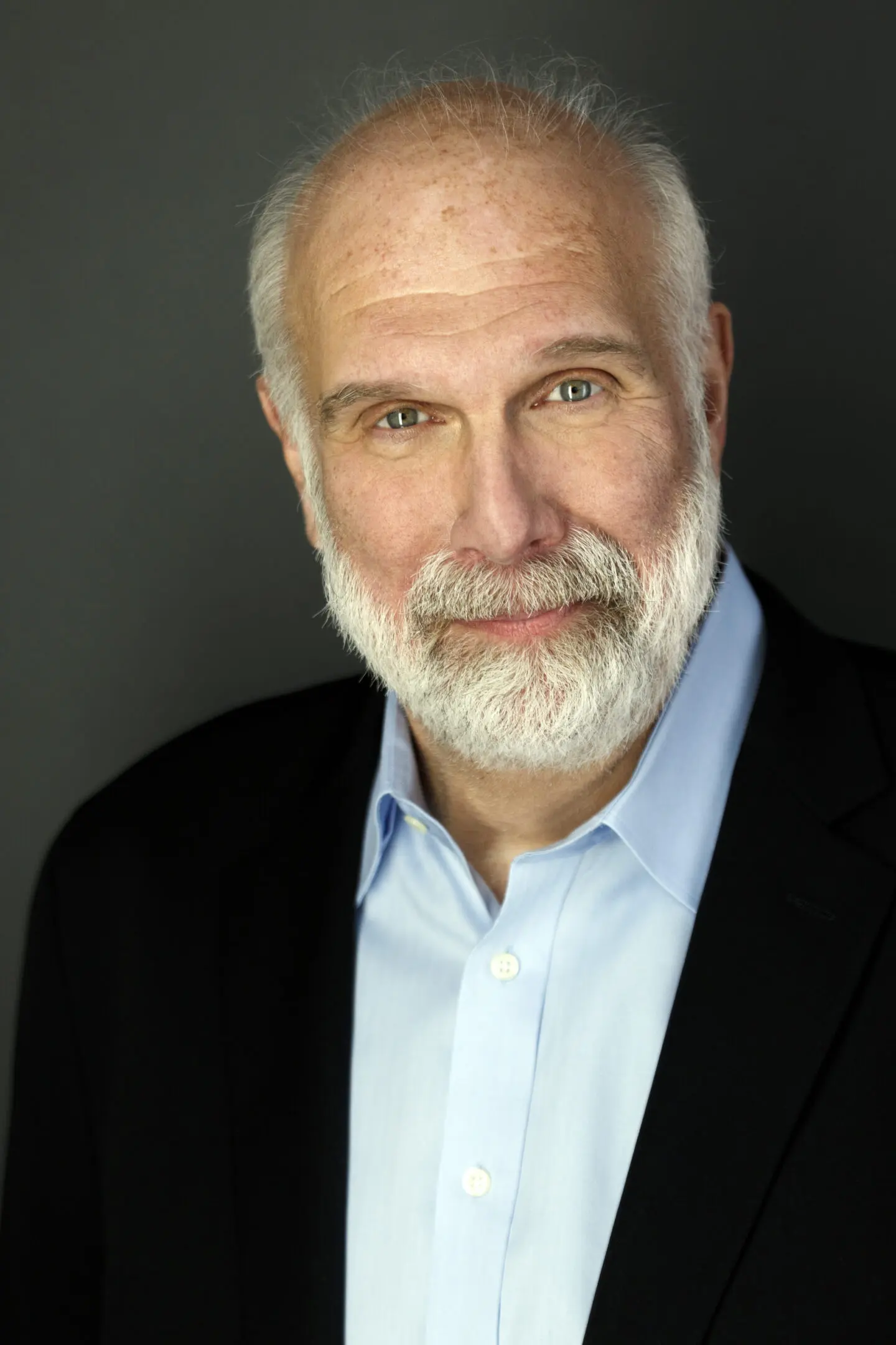 685ae9c197d69_Bio headshot by Jeremy Folmer Portrait of a distinguished older man with a white beard and light blue shirt.